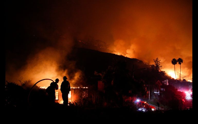 Bomberos observan mientras una casa arde en la ciudad californiana de La Conchita, Estados Unidos. Los incendios en el estado han forzado la evacuación de miles de habitantes. AP/J. C. Hong