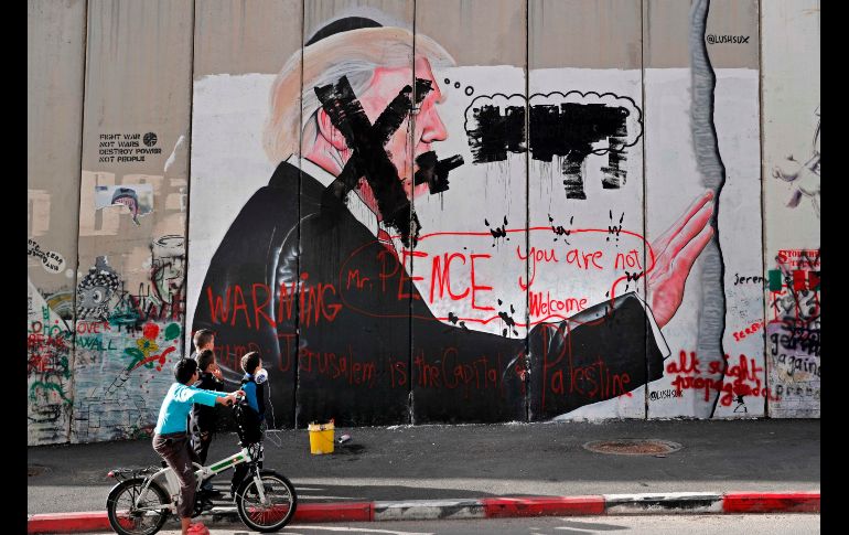 Niños miran un graffiti vandalizado con la imagen del presidente de EU, Donald Trump, en la barrera de separación en Belén, Cisjordania, durante protestas de palestinos tras de que Trump reconociera a Jerusalén como capital de Israel. AFP/T. Coex