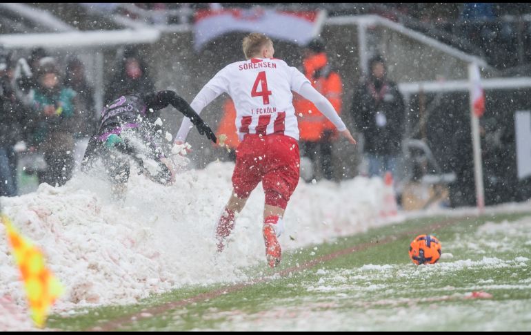 Frederik Soerensen (d), defensa del Colonia, y Marco Terrazzino, del Freiburgo, disputan un balón junto a nieve acumulada durante un partido de la Bundesliga en Colonia, Alemania. AFP/DPA/G. Kirchner