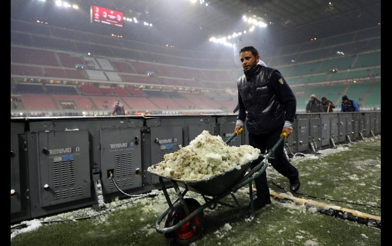 Trabajadores remueven nieve de la cancha previo a un partido de entre el Milán y Bologna, en Milán, Italia.