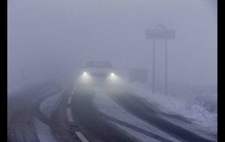 En Reino Unido, las importantes nevadas del domingo causaron problemas en los transportes carreteros, ferroviarios y aéreos. Un auto avanza lentamente entre la niebla y sobre un camino en Derbyshire.