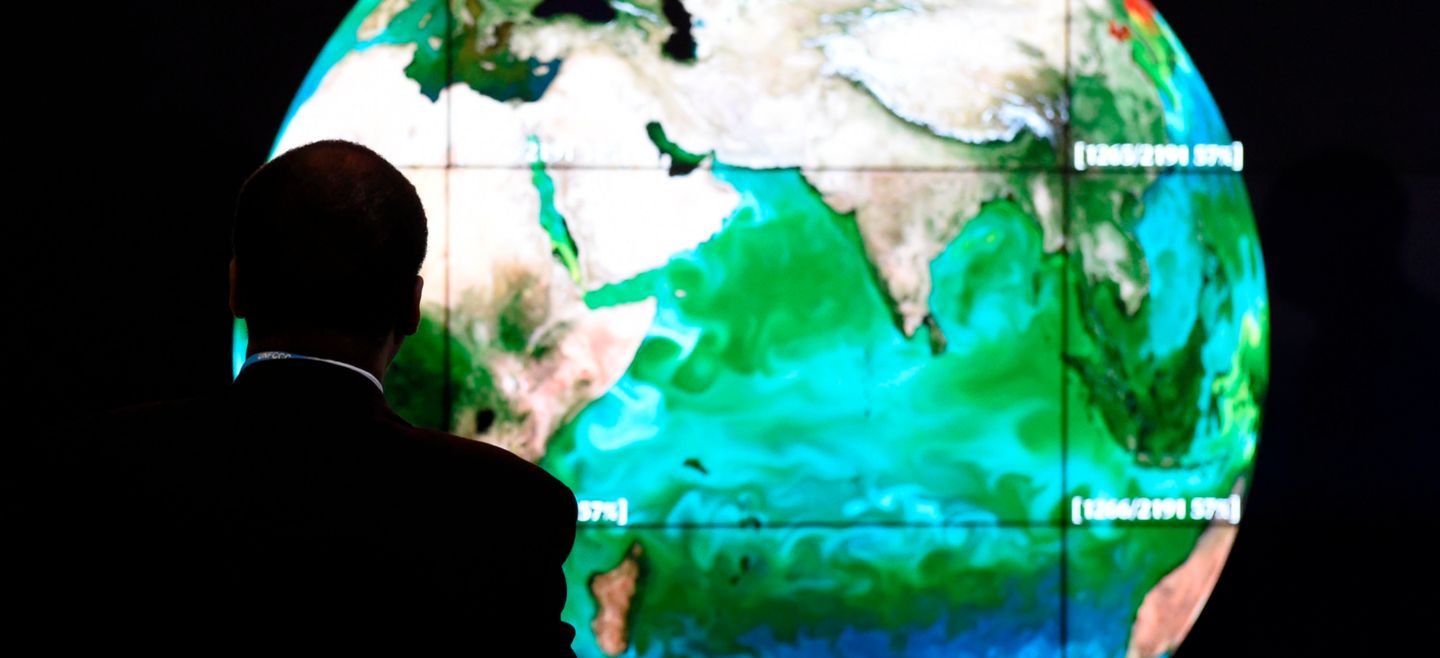 - - (FILES) This file photo taken on November 30, 2015 shows a conference attendee looking at a projection of the Earth  on the opening day of the COP 21 United Nations conference on climate change, on November 30, 2015 in Le Bourget, on the outskirts of the French capital Paris.  Two years after the adoption of a historic global warming pact ahead of the One Planet Summit, sponsored by France, the United Nations and the World Bank, brings together some 4,000 participants and 800 organizations to explore ways to finance climate projects on December 12, 2017. / AFP / ALAIN JOCARD FILES-FRANCE-CLIMATE-WARMING - TO GO WITH AFP STORY BY CATHERINE HOURS