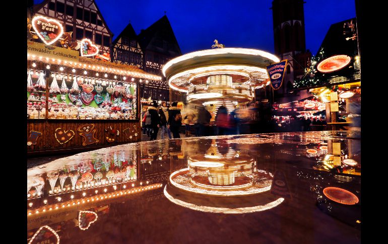 Un carrusel se refleja en un recipiente con agua en el mercado navideño de Fráncfort, Alemania. AP/M. Probst