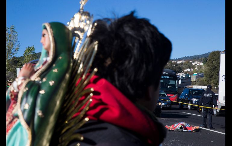 Un peregrino con una figura de la virgen de Guadalupe observa la zona del accidente.