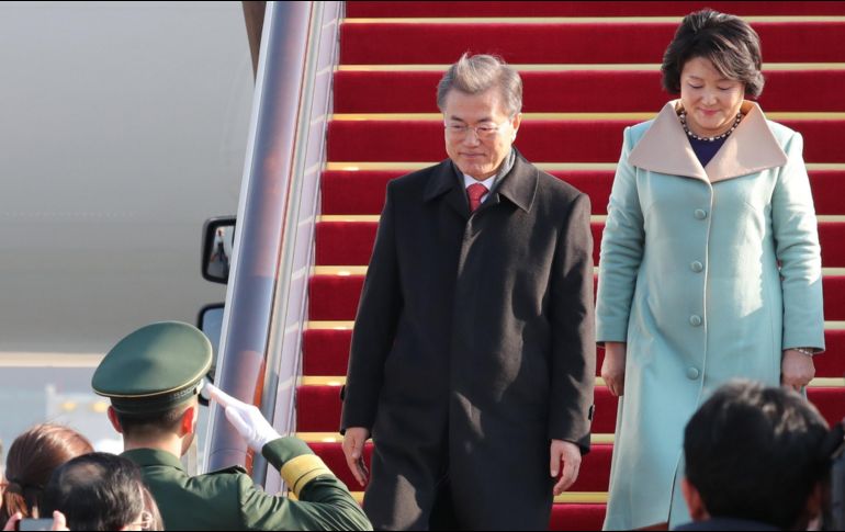 El presidente surcoreano, Moon Jae-in (c), y la primera dama Kim Jung-sook descienden del avión a su llegada a Pekín. EFE/YONHAP