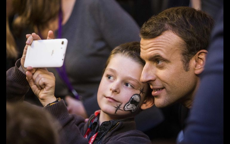 El presidente de Francia, Emmanuel Macron, posa para una foto con un niño, en el marco de una ceremonia navideña con niños en el Palacio del Elíseo en París. AFP/E. Laurent