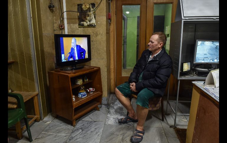 Un hombre mira la transmisión en vivo de la conferencia de prensa anual del presidente ruso, Vladimir Putin, en la entrada a un edificio en Moscú. AFP/V. Maximov