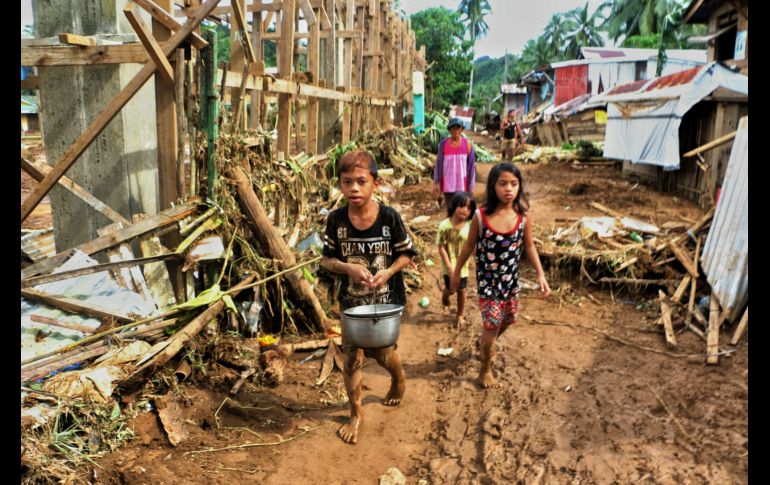 Niños pasan junto a escombros y casas dañadas por la tormenta tropical 