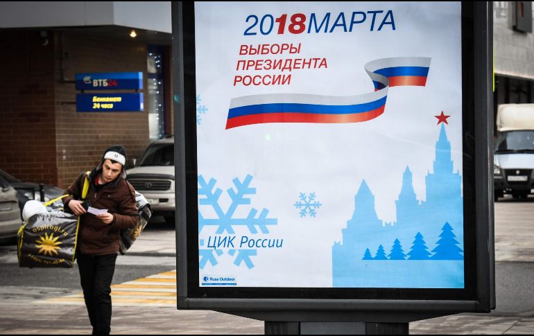 Un hombre camina junto a un póster que anuncia las elecciones del próximo año. AFP/M. Antonov