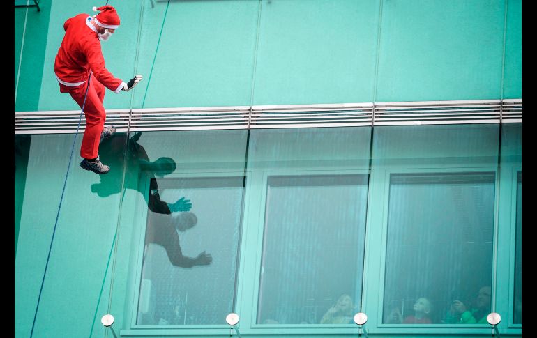 Un hombre en disfraz de Santa Claus saluda a niños al bajar del techo de una clínica pediátrica en Ljubljana, Eslovenia. AFP/J. Makovec