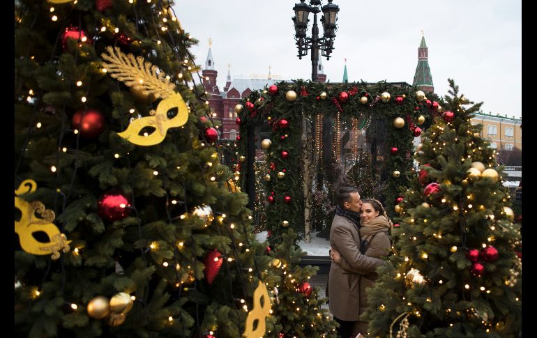 Una pareja se abraza entre la decoración navideña colocada en la plaza Manezhnaya, en Moscú. AP/P. Golovkin