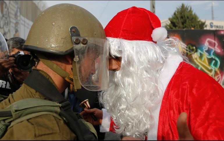 Un hombre palestino vestido de Santa Claus discute con un soldado israelí en Jerusalén. AP / N. Shivoukhi