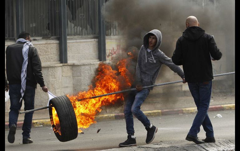 Un palestino sostiene una llanta prendida durante enfrentamientos en Belén con fuerzas israelíes, en el marco de una protesta contra la decisión de Donald Trump de reconocer a Jerusalén como capital de Israel. AFP/M. Al Shaer