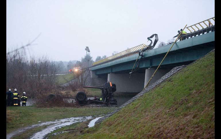 Bomberos inspeccionan la escena del accidente de un camión, en Pila, Polonia. El vehículo, que transportaba troncos de madera, se precipitó y cayó al río Gwda. El conductor falleció. EFE/J. Kaczmarczyk