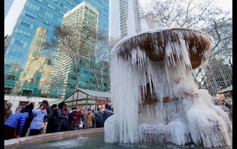 Personas se toman fotos junto a una fuente con agua congelada en el parque Bryant  de la ciudad de Nueva York. Tormentas de nieve y un corriente de aire ártico han provocado temperaturas bajo cero en la región. AP/F. Franklin II