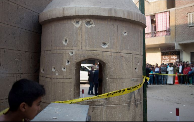 Un curioso observa las labores de las autoridades junto a una pared tiroteada próxima a la iglesia. EFE/M. Hossan