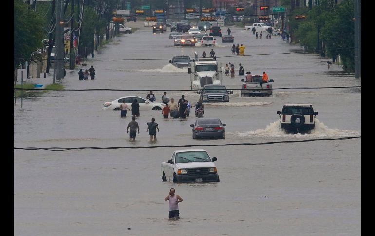 HOUSTON, ESTADOS UNIDOS (27/AGO/2017).- Personas y vehículos transitan por la calle Telephone. La tormenta ha provocado además el cierre de los dos aeropuertos más importantes de Houston, que dejaron 100 vuelos cancelados. AFP/T. Shea