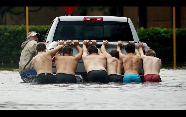 HOUSTON, ESTADOS UNIDOS (27/AGO/2017).- Hombres empujan un pick up varado. AP/C. Riedel