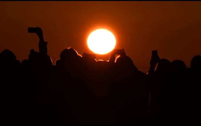 Desde un observatorio, personas toman fotos mientras el Sol sale sobre la Bahía de Tokio, en Japón. AFP/T. Kitamura
