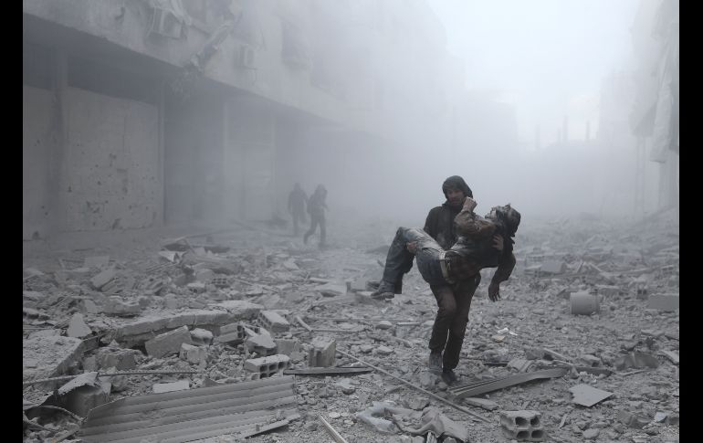 Un hombre carga a un herido tras un ataque aéreo en la población siria de Arbin, controlada por los rebeldes. AFP/A. Eassa
