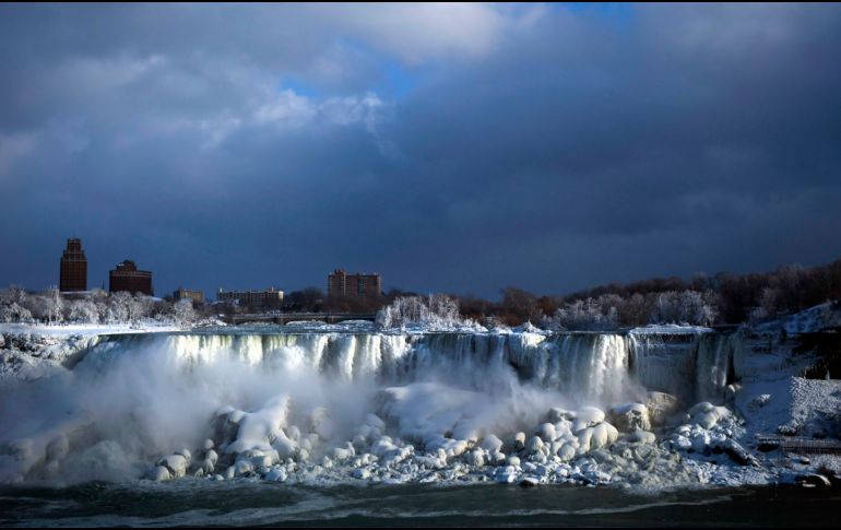 El agua fluye sobre las cataratas del Niágara del lado estadonunidense mientras se forma hielo por el clima gélido, en una toma desde el lado canidense en Niagara Falls. AP/The Canadian Press/A. Lynett