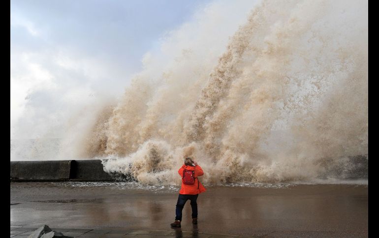 Una mujer toma fotos en el malecón de New Brighton, Inglaterra. En el noroeste del país, los vientos alcanzaron a los 160 kilómetros por hora.