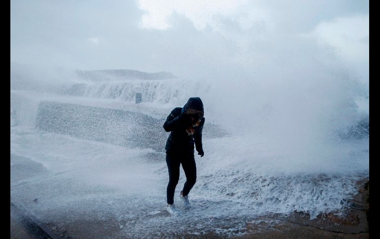 Una mujer se cubre de las olas que azotan en Auderville, Francia. Unos 200 mil hogares en el norte de Francia se quedaron sin electricidad y el fuerte oleaje en el océano Atlántico hacía prever inundaciones.