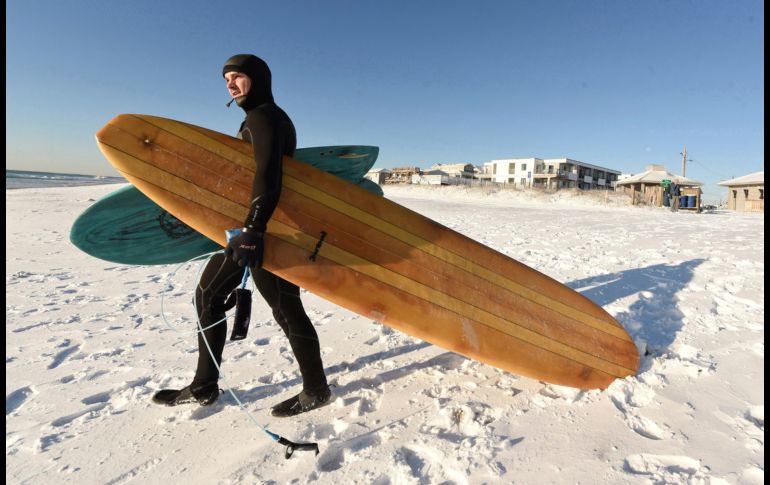 Kevin Cagle se dirige a surfear en Wrightsville Beach, Carolina del Norte. En la zona se registran unos ocho centímetros de nieve
