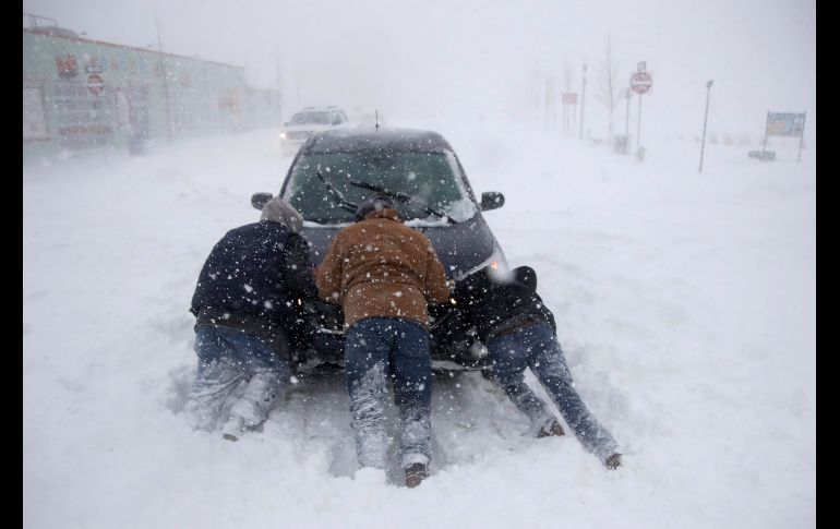 Personas ayudan a empujar un auto atascado en Asbury Park, Nueva Jersey. La tormenta amenaza con dejar a millones sin luz y recién amainará el viernes, al avanzar hacia Canadá.