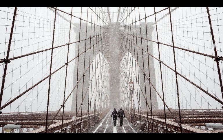 Peatones cruzan el puente de Brooklyn durante una tormenta de viento y nieve en Nueva York, Estados Unidos. La ciudad y vastas áreas del estado de Nueva York estaban en estado de emergencia por el clima. EFE/J. Lane