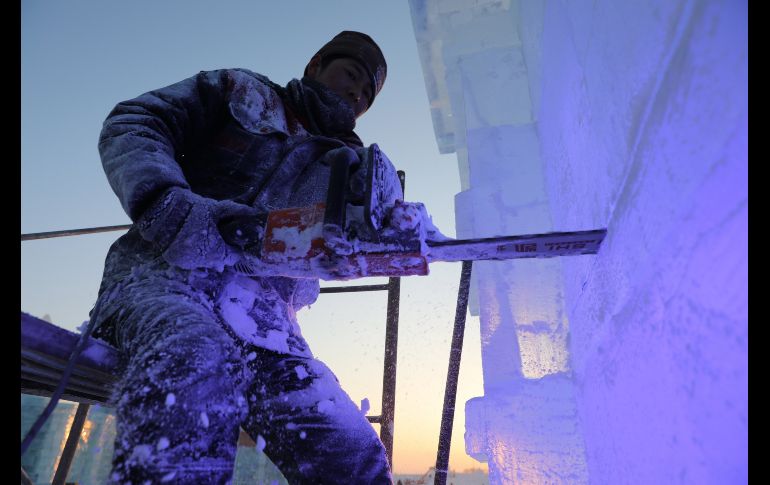 Un operario trabaja en la construcción de una escultura de hielo.