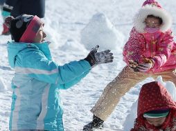 Varios niños juegan en medio de la nieve en una de las comunidades afectadas por el temporal. EFE/YONHAP