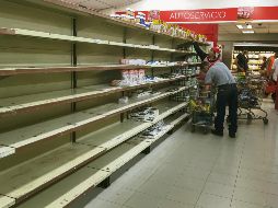 Trabajadores de un supermercado ordenan los estantes, tras la llegada de cientos de personas a comprar la mercancía a la que se le bajó el precio. EFE