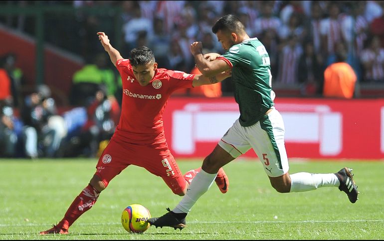 En la foto, Alexis Vega del Toluca pelea por el balón con Hedgardo Marín, de Chivas. AFP / R. Vázquez