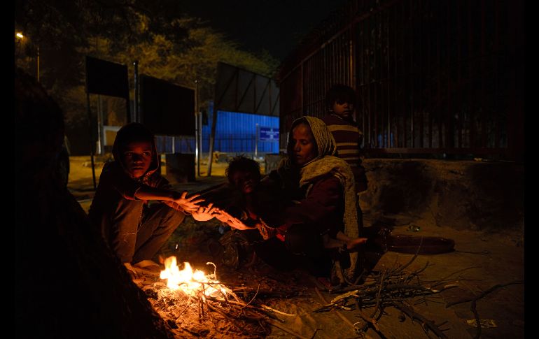 Una familia se calienta junto a una fogata junto a un camino en Nueva Delhi, India. AFP/S. Hussain