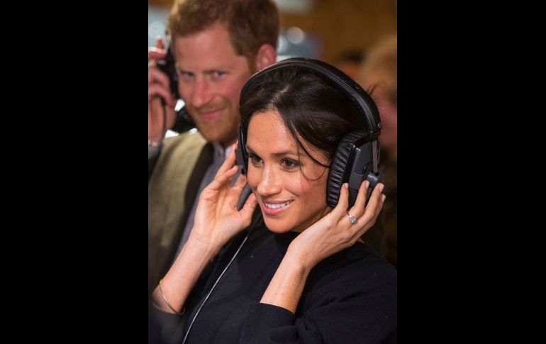 El príncipe Enrique de Inglaterra y su prometida Meghan Markle usan audífonos durante una visita a la estación de radio Reprezent 107.3 FM, en Londres, para observar un modelo de apoyo a jóvenes. AP/D. Lipinski