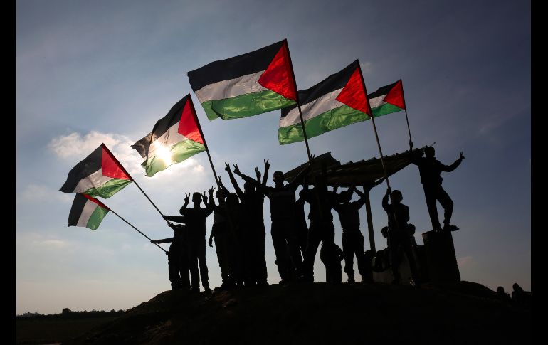 Palestinos ondean su bandera nacional en Khan Yunis, cerca de la frontera entre Gaza e Israel, en protesta contra la petición de Israel de desaparecer la Agencia de Naciones Unidas para los Refugiados de Palestina en Oriente Próximo. AFP/S. Khatib