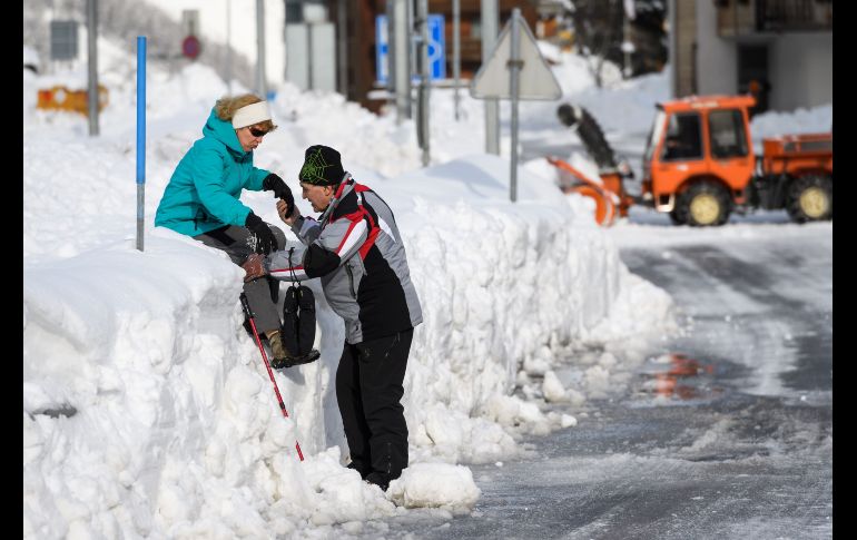 Un hombre ayuda a su esposa a pasar una pared de nieve.