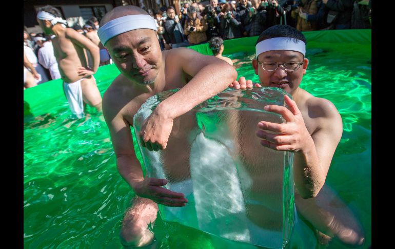 Dos hombres sostienen un bloque de hielo durante el tradicional baño de hielo en el templo Teppozu Inari en Tokio, Japón. Cerca de 100 personas han participado en esta ceremonia. EFE/C. Jue