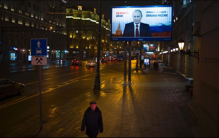 Un hombre pasa cerca de un póster de la campaña del presidente Vladimir Putin en el cual se lee 