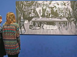 Réplica. Dos personas miran una fotografía del cuadro de Frida Kahlo. AFP