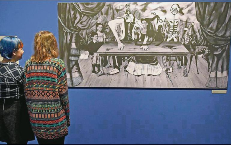 Réplica. Dos personas miran una fotografía del cuadro de Frida Kahlo. AFP