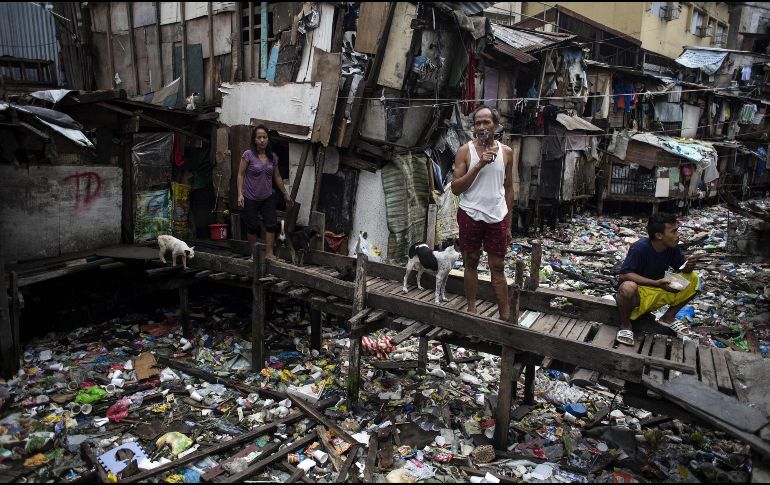 Habitantes descansan en un puente sobre un canal de agua lleno de basura en Manila, Filipinas. AFP/N. Celis