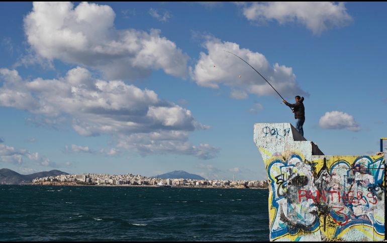 Un hombre pesca durante un día con viento en el distrito Alimos de la capital griega, Atenas. AP/P. Giannakouris