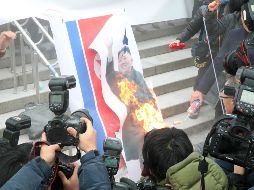 Manifestantes queman un retrato del líder norcoreano luego de leer un comunicado de repudio. AFP/D. Ilbo