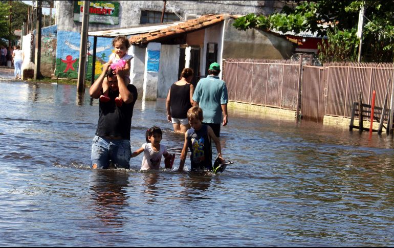 Personas caminan en una calle inundada de Asunción, Paraguay. Vecinos de barrios en las orillas del río Paraguay se afanan hoy, después de una semana de inundaciones, en mudarse a zonas más altas de la ciudad. EFE/A. Cristaldo