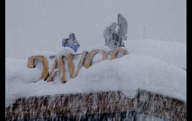 Oficiales suizos armados vigilan desde un techo durante una nevada.