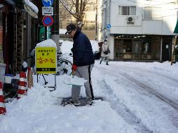 Un hombre despeja la nieve de una acera después de una nevada en Tokio. EFE/F. Robichon
