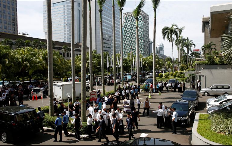 Varios trabajadores aguardan fuera de un edificio en Yakarta. EFE/A. Weda