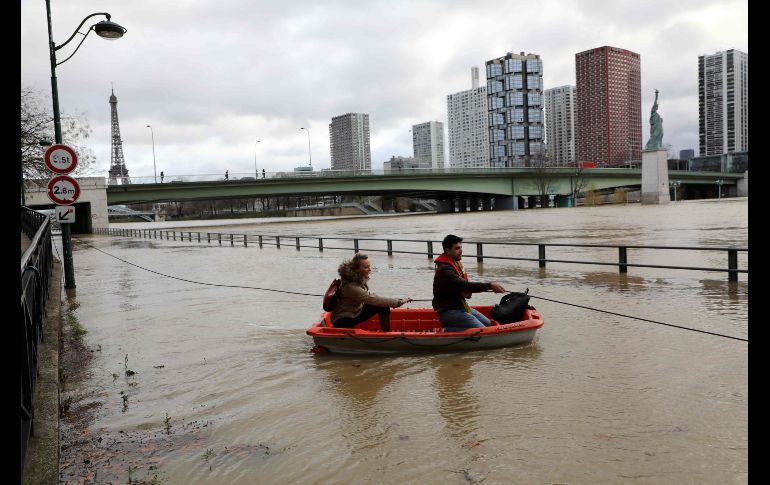 Personas usan un bote para acceder a una casa flotante tras el desbordamiento del río Sena en París.